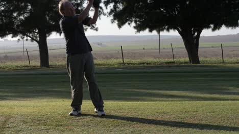 golfer swings a wood on the fairway on a south african golf course, slow motion and wide