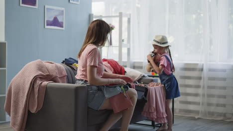 little girl helps mother to gather items for voyage on couch