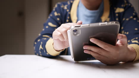 holding a mobile tablet with one hand and browsing the internet with the other hand, an individual is checking for some updates on the newsfeed