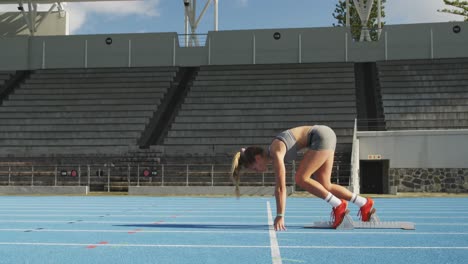 vista lateral de un atleta caucásico preparándose para una carrera en un estadio