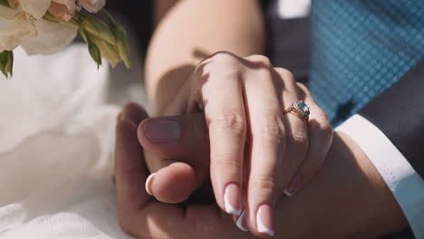 young bride and groom join hands sitting at wedding ceremony