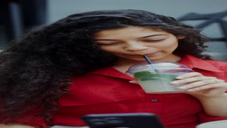 joven disfrutando de limonada y usando el teléfono en un café