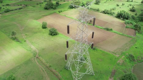 high voltage overhead transmission lines being placed in rural areas of india - aerial drone footage - electricity pylons and high voltage power line