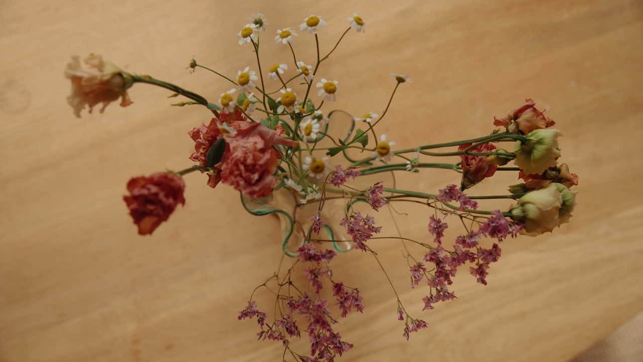 Ripresa dall'alto di fiori in un vaso su un tavolo di legno