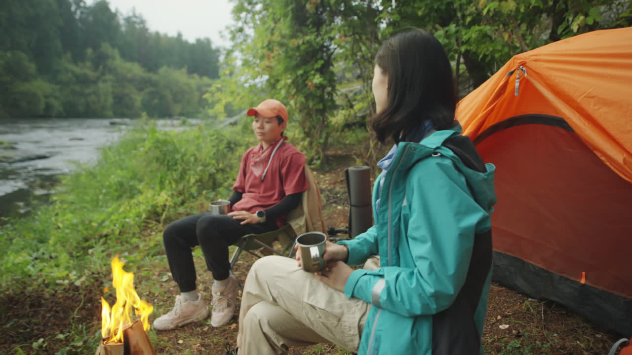 Asian Female Tourists Drinking Tea by Campfire