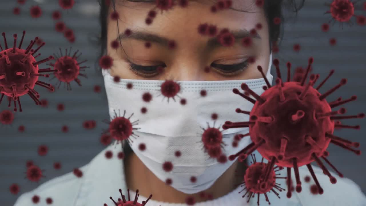 Animation of covid cells floating over portrait of woman wearing face mask in city street