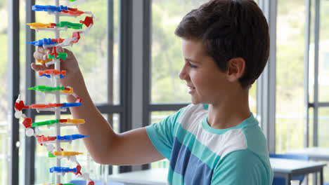 escolar atento experimentando con un modelo de molécula en el laboratorio