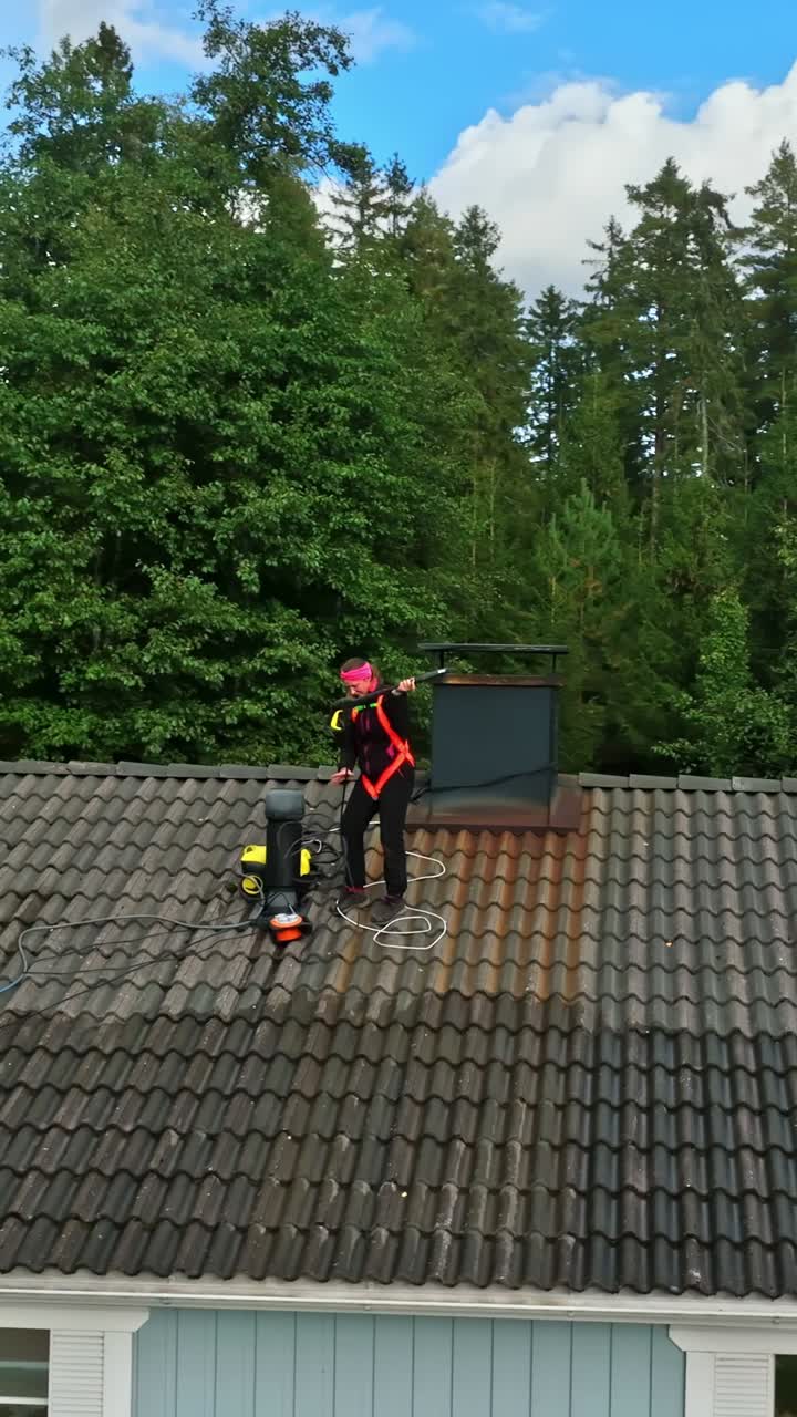 Aerial portrait orbiting of a woman gearing up for cleaning work on house roof