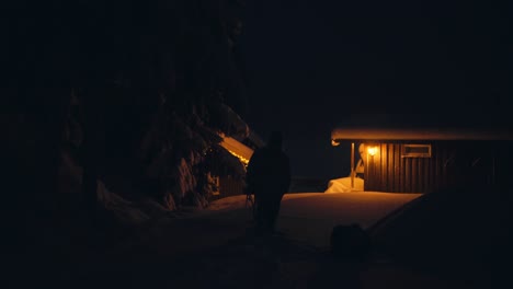 silhouette of a man and his pet dog outside the house on a winter night