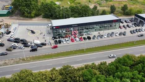 motorway going along the new car dealership. people look at multiple autos and helicopter near the centre.