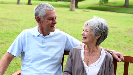 Retired-couple-sitting-on-a-park-bench-talking-