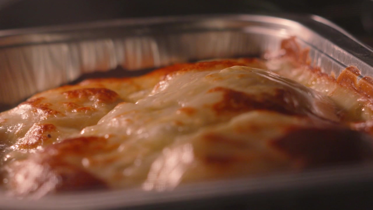 Ripresa rotante attorno a patate gratinate alla Dauphinoise che cuociono nel forno. Perfetto per documentari culinari, marchi di alimenti di lusso o promozioni di ristoranti.