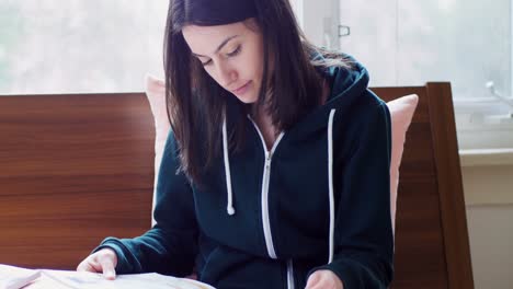 mujer joven con capucha leyendo revista 4k
