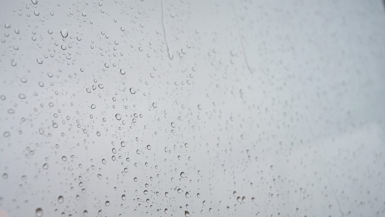 un video en cámara lenta de fuertes gotas de lluvia aterrizando en un vidrio de la ventana