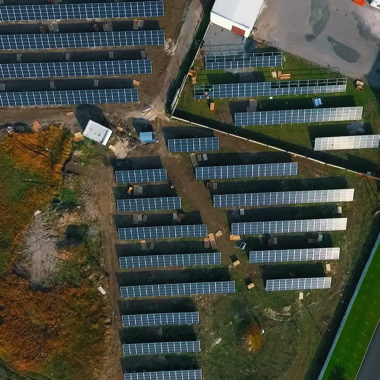 Solar panels at sunlight. Solar power station for production of green energy. Small solar farm on field in the countryside. Top view. Camera rising