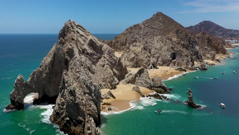 drone shot of el arco and playa del amor with boats in the ocean in cabo san lucas mexico