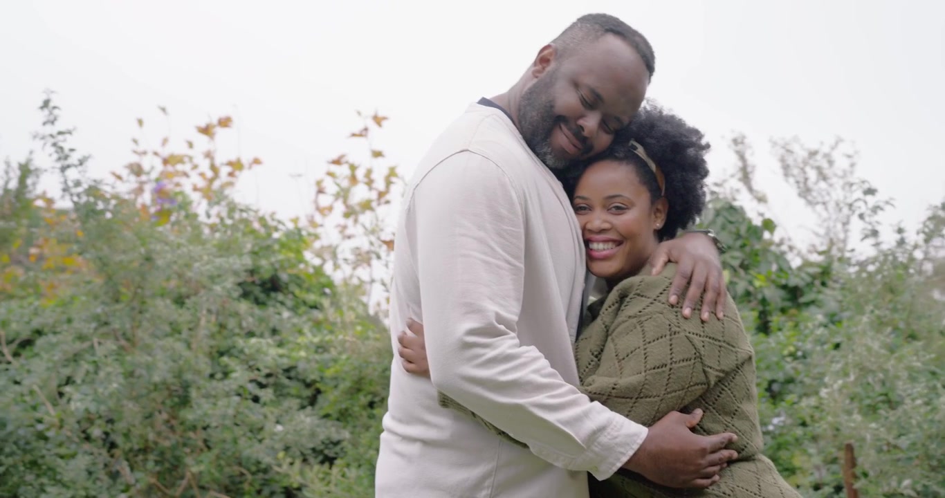 African couple locking eyes, reaching hands, hugging in garden, reuniting, watch, headband, stake