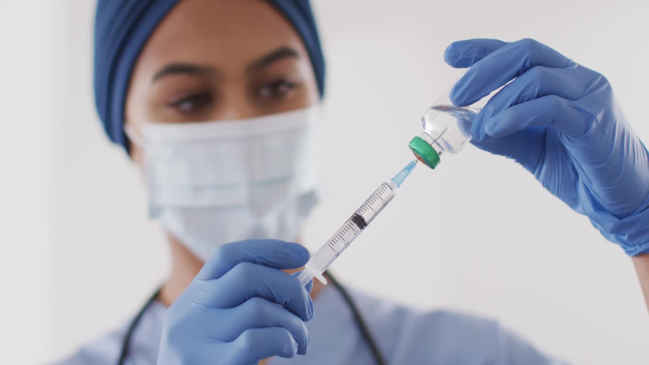 Nurse inserting needle into vial, drawing dose while DNA helix moving across frame covering syringe