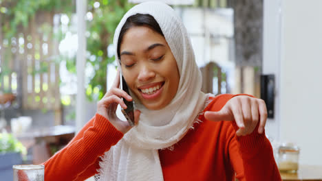 Woman-talking-on-mobile-phone-in-cafeteria-4k