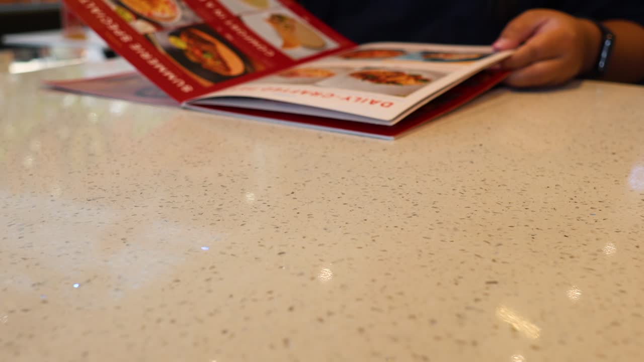 manos navegando por un menú en una mesa