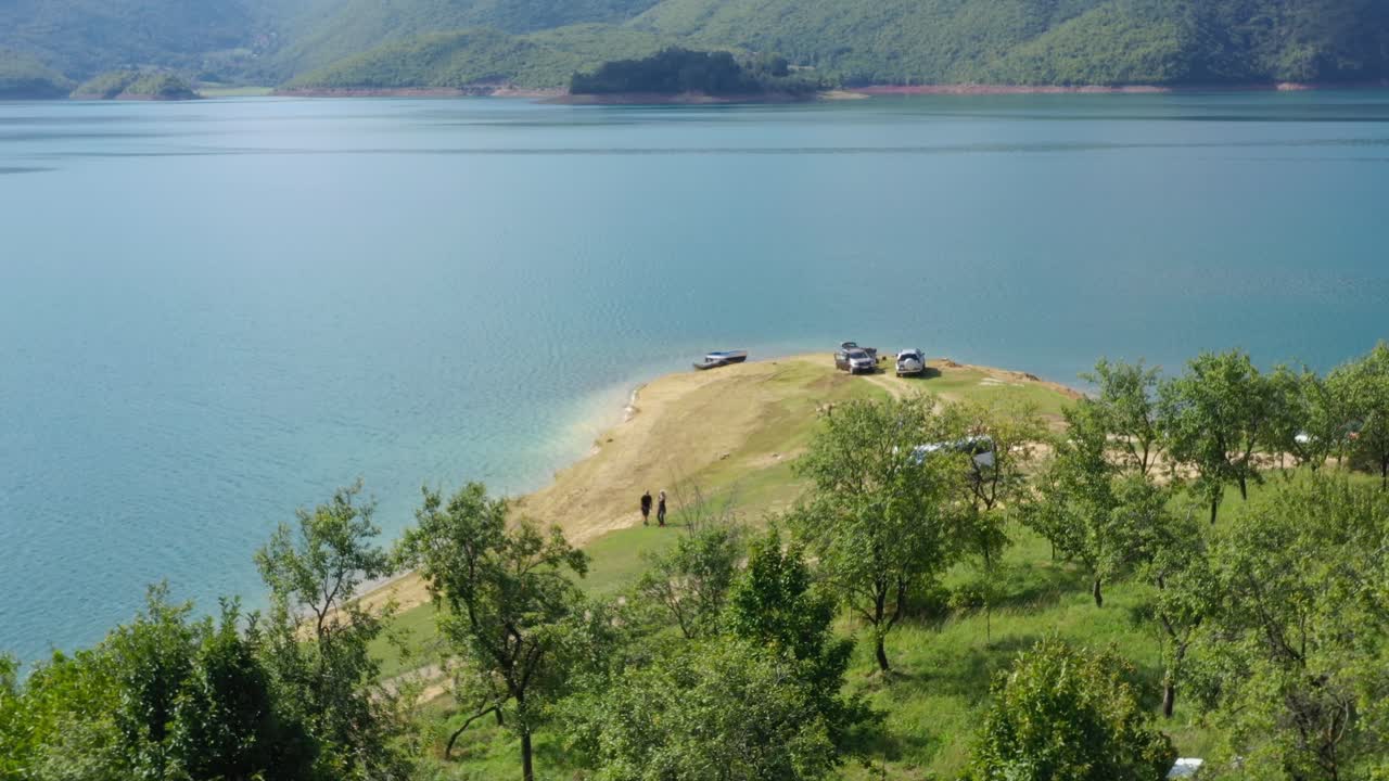Rama Lake in Bosnia and Herzegovina with Cars parked near shore making a camp site, Aerial dolly in shot