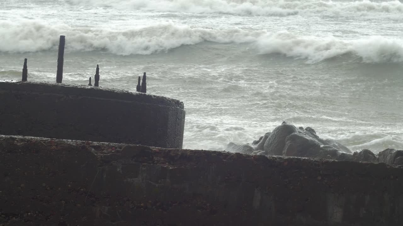 폭풍우에 버려진 콘크리트 해안 방어 건물 폐허를 강타하는 큰 파도