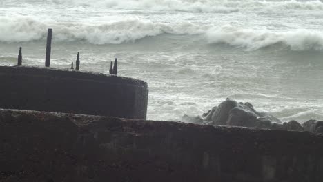 big waves hitting the abandoned concrete coast defense building ruins in stormy weather