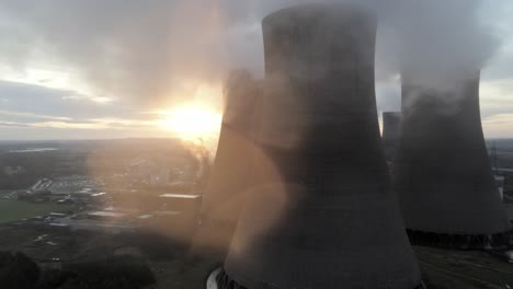 aerial dolly right uk power station cooling towers smoke steam emissions, sunrise hiding behind chimney stack