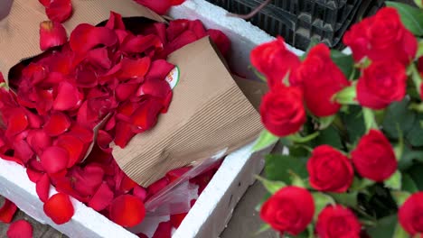 los pétalos de rosas rojas se ven en el suelo mientras se ve una boutique de rosas a la venta en un mercado de flores durante el día de san valentín
