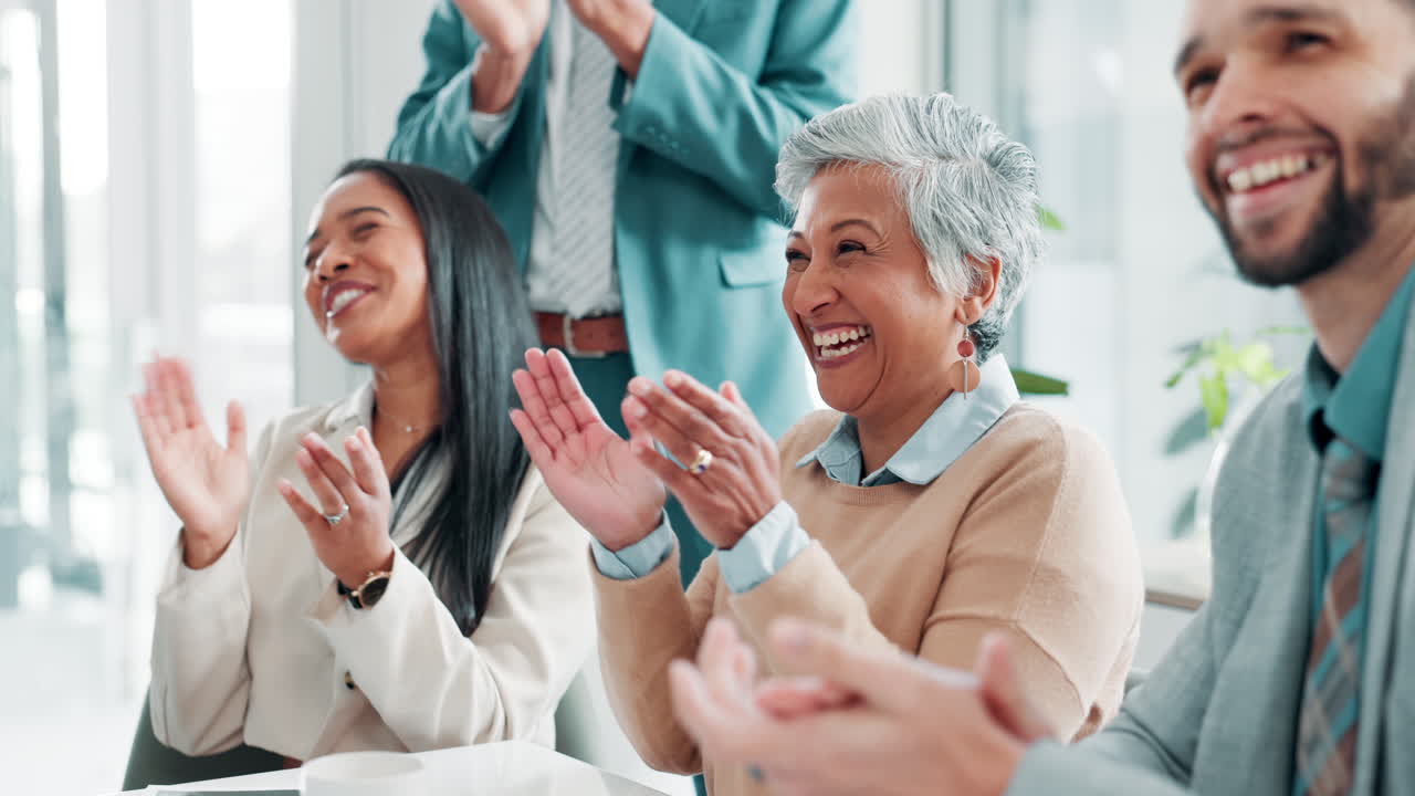A group of diverse business professionals clapping and celebrating success during a meeting