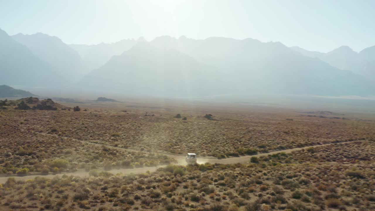 공중: 은색 세단이 산악 지형의 길에서 모이를 돌고 있습니다.