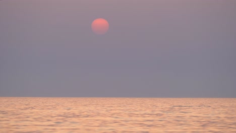 beautiful setting sun at the sea horizon, boat crossing on idyllic sunset colors, crete