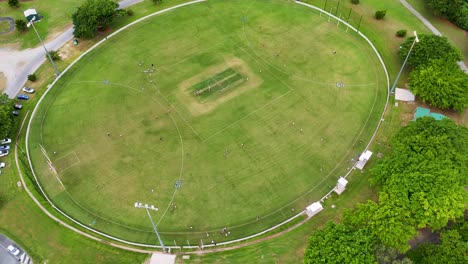 drone footage captures a sports field surrounded by greenery in port douglas, australia, under bright daylight