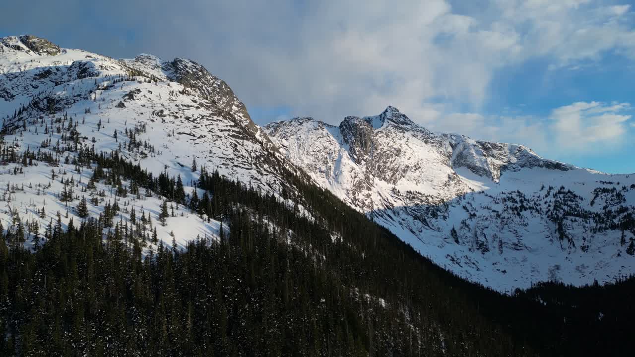 picos de montañas rocosas con nieve y árboles