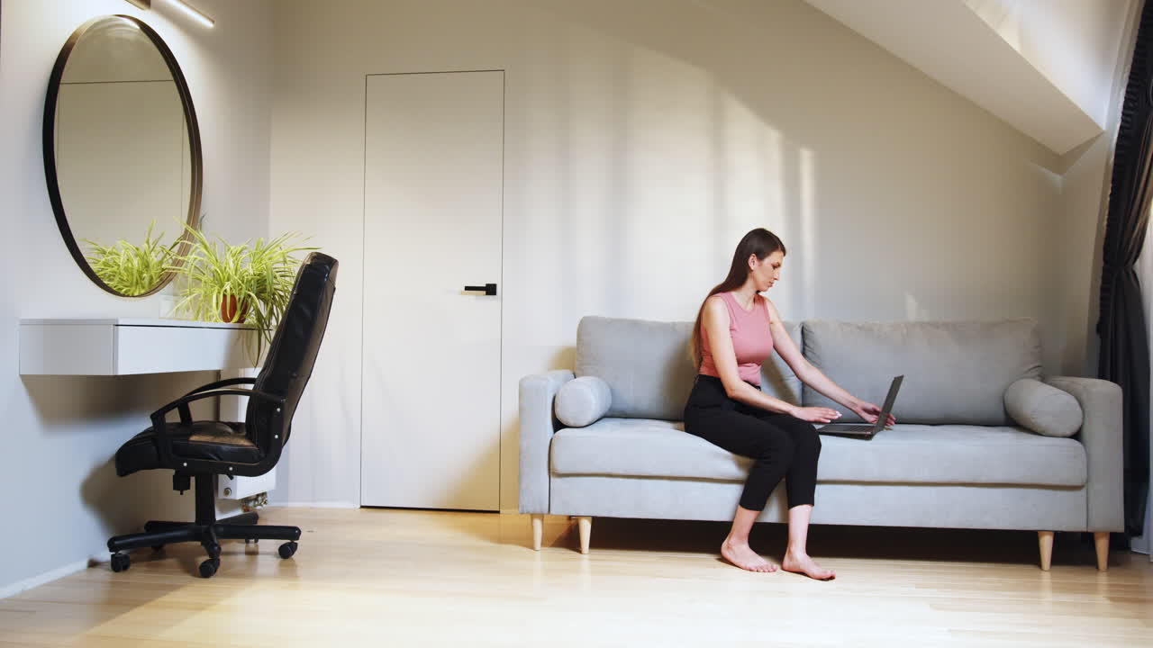mujer trabajando desde casa en un sofá