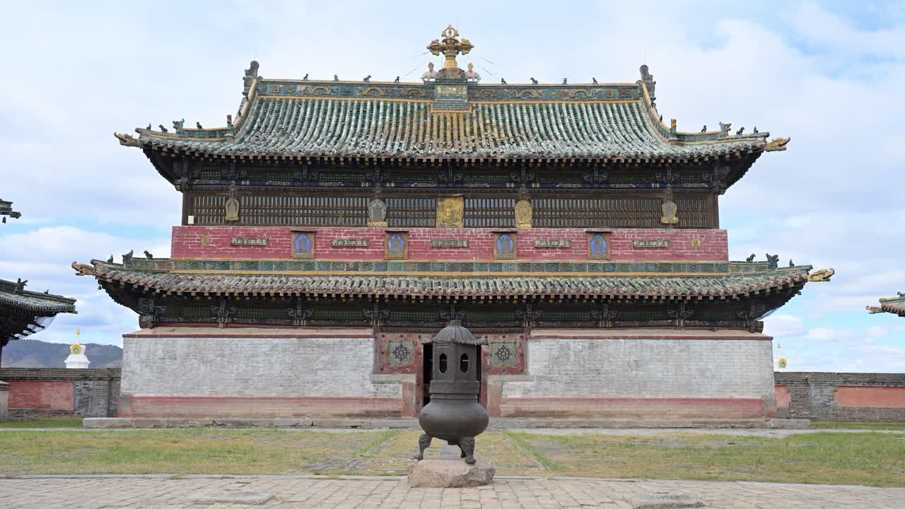 Ornate temple pavilion at Erdene Zuu Monastery, Mongolia. A golden Dharma Wheel and deer sculptures sit atop green tiled eaves, showcasing the artistry of the country's oldest religious site