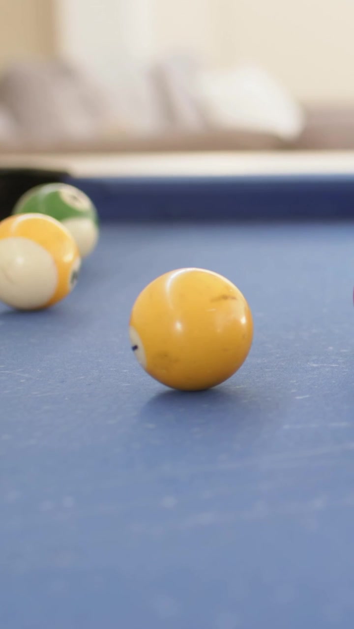 Vertical video: Yellow ball rolling center on pool table after break, green ball stopping at rail