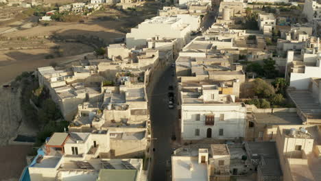 Calle-Vacía-Que-Atraviesa-Un-Pequeño-Pueblo-Mediterráneo-En-Un-País-En-Desarrollo-Con-Casas-De-Color-Arena-Beige-Marrón,-Drones-Aéreos-Hacia-Delante