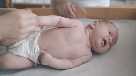 boy-lies-on-changing-table-and-nurse-practices-arm-massage