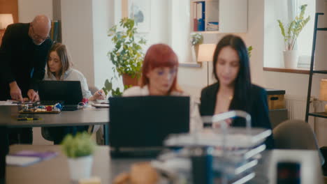 female coworkers discussing at desk in office.