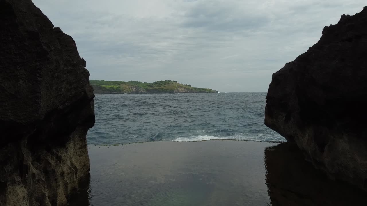 Aerial flight between Devil's Billabong with ocean at Nusa Penida, Bali during cloudy day