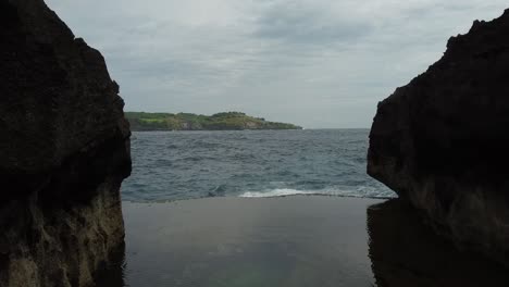 Vuelo-Aéreo-Entre-Billabong-Del-Diablo-Con-El-Océano-En-Nusa-Penida,-Bali-Durante-El-Día-Nublado