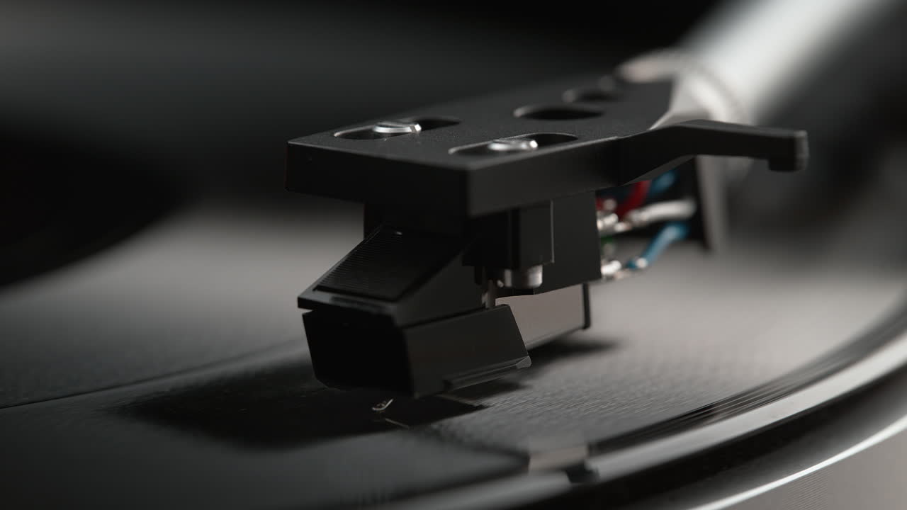 마운트 된 스타일러스를 가진 자기 카트리지가 회전하는 비닐 레코드의 경로를 따라 느린 동작으로 슬라이드됩니다.