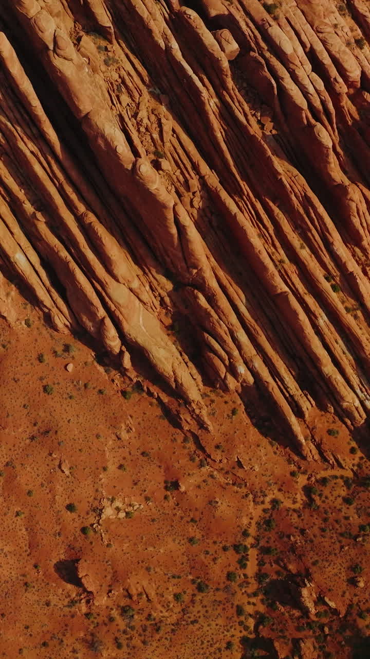 Stunning rocks of American canyons on sunny daytime. Highway road passing through the dry desert in Utah State from top view. Vertical video