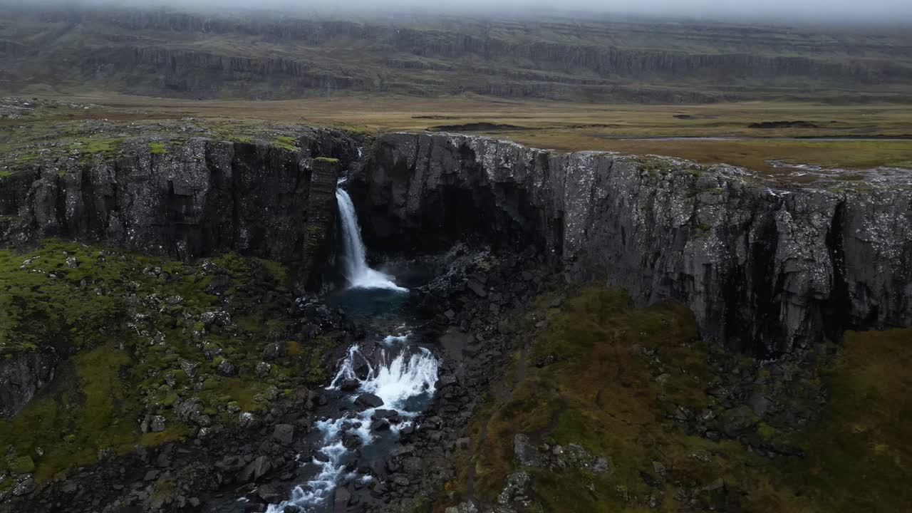cascada de snaedalsfoss fuera del acantilado en un paisaje nublado y sombrío de islandia, aero