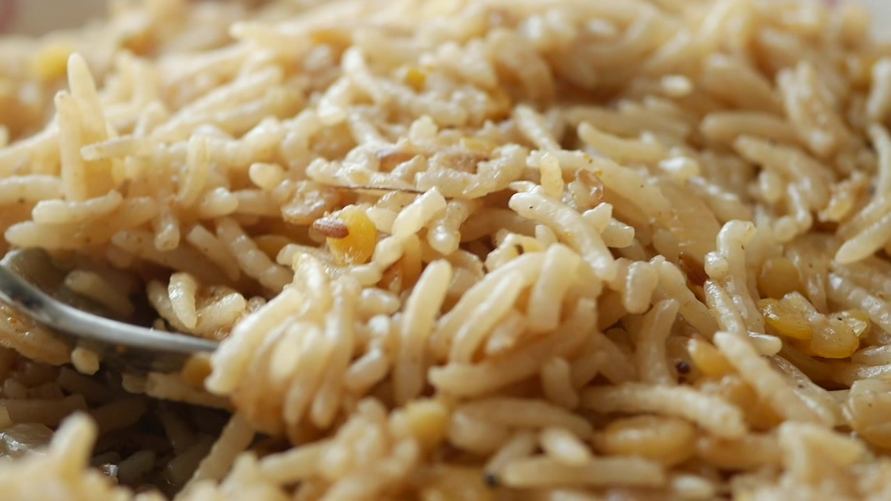 Primo piano di un cucchiaio che solleva riso e lenticchie fumanti