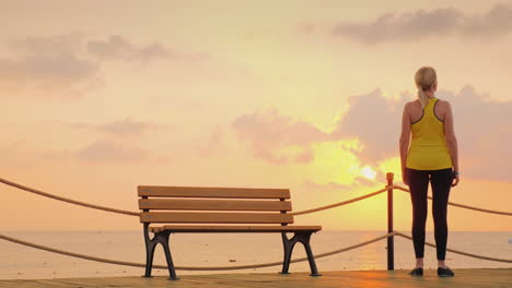 A-Woman-Looks-At-The-Amanecer-Against-A-Beautiful-Dramatic-Sky-It-Stands-On-Full-Length-On-A-Wooden-P