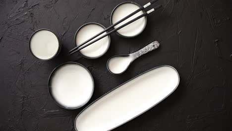 Set-of-empty-ceramic-dishes-for-sushi-and-rolls-on-a-black-stone-table