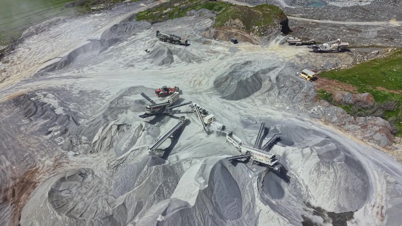 Granite quarry site showing heavy machinery and gravel piles during daytime