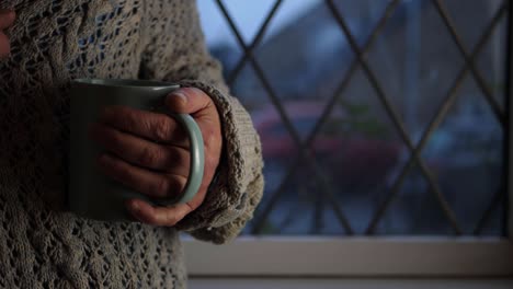 woman with mug of hot drink in window medium shot